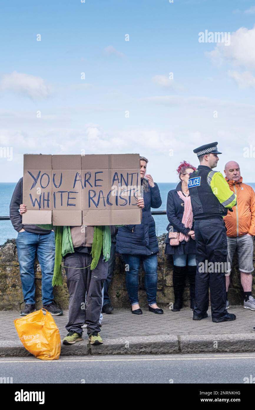 A protester holding a hand written cardboard placard at a demonstration organised by the right wing group Reform UK against asylum seekers placed in t Stock Photo