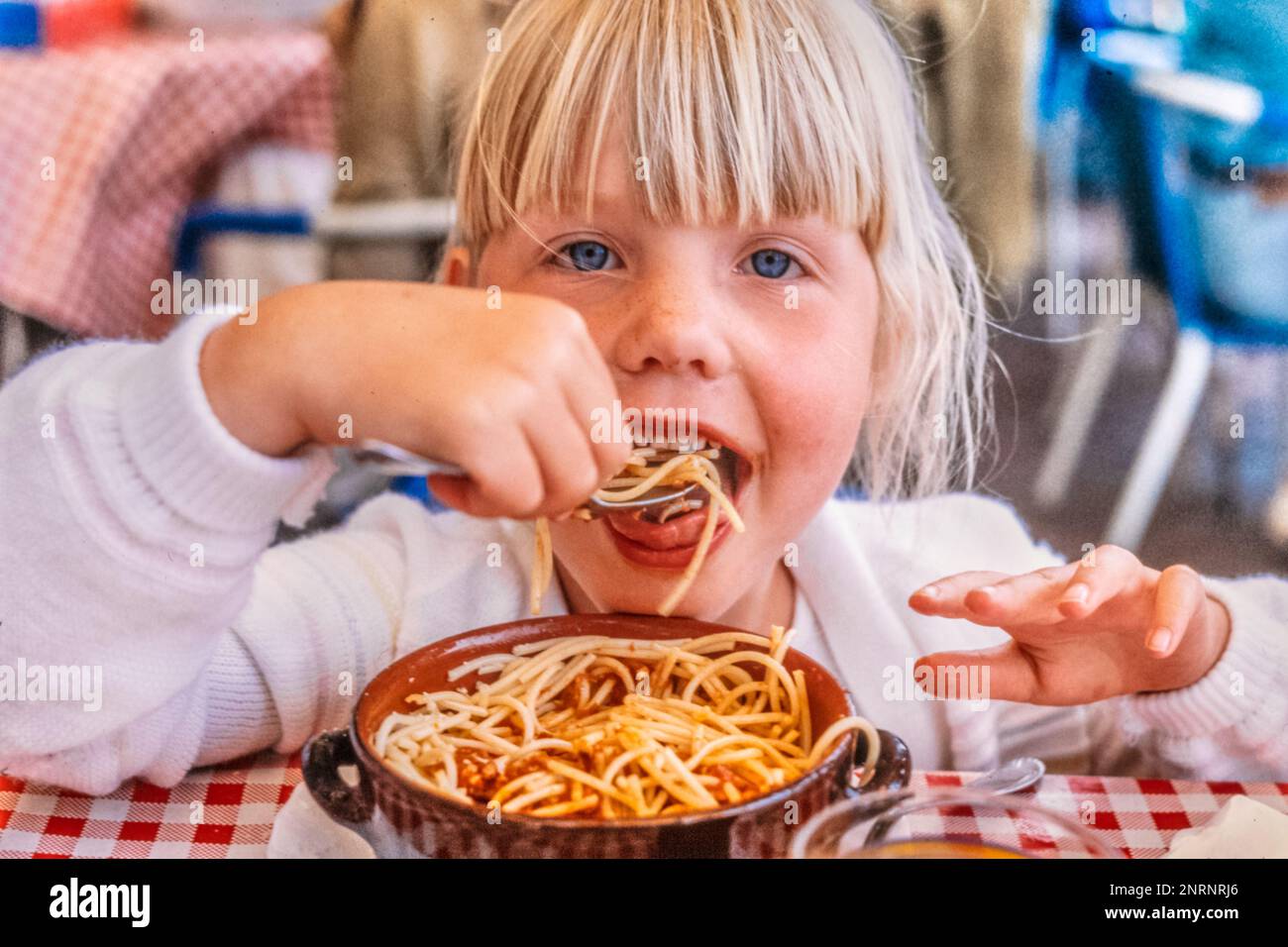 Child eating spaghetti bolognese, Daughter on holiday in an italian restaurant enjoying meal. Stock Photo