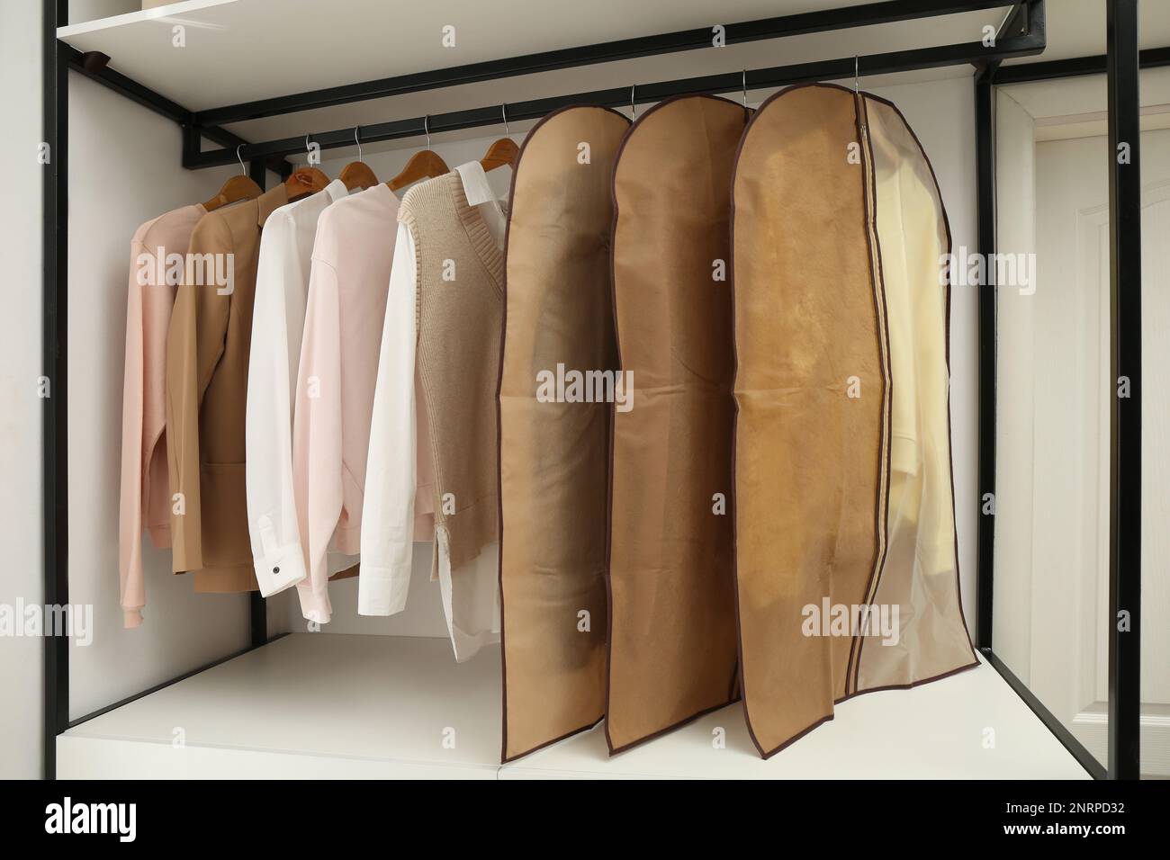 Garment bags with clothes on rack in dressing room Stock Photo Alamy