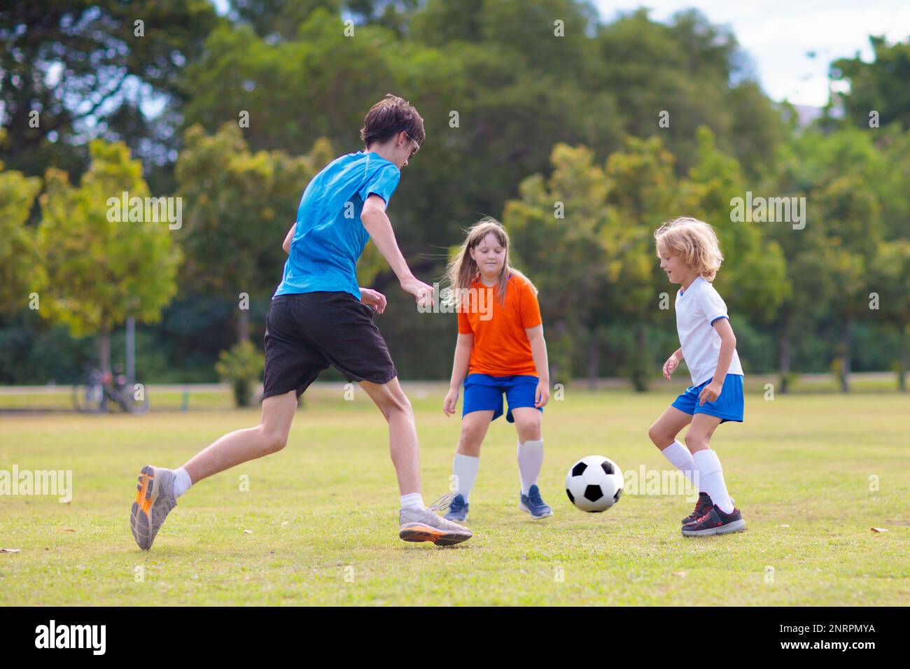 Kids play football on outdoor field. Children score a goal at soccer