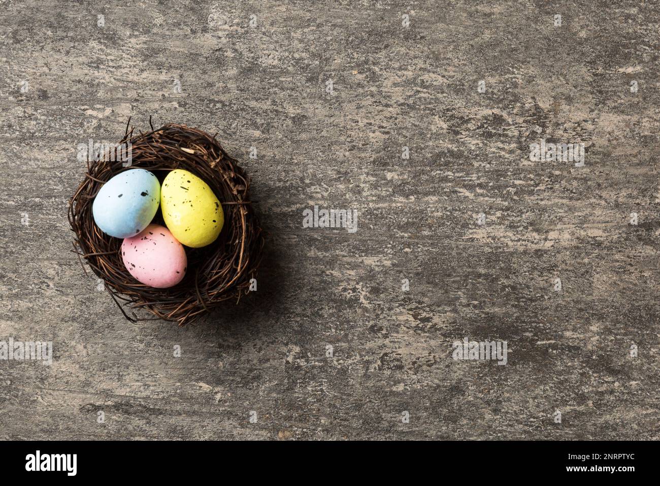 Colorful easter eggs in nest on table background with copy space top ...