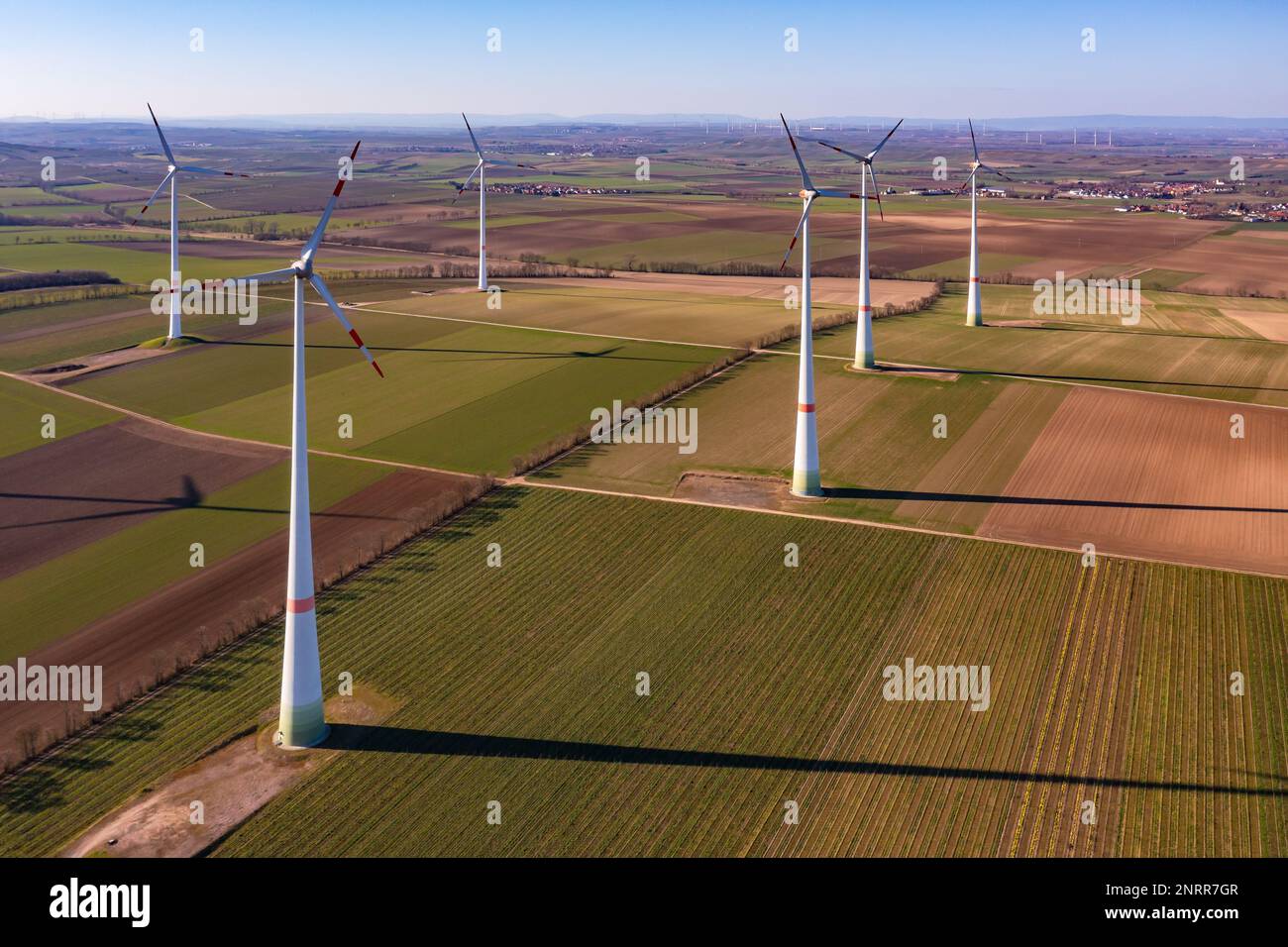 Aerial view of tall wind turbines between fields in the winter sun Stock Photo