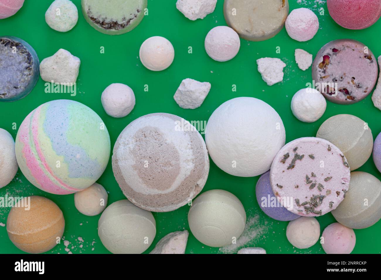 Multicolored bath bombs on a green background, top view. Stock Photo