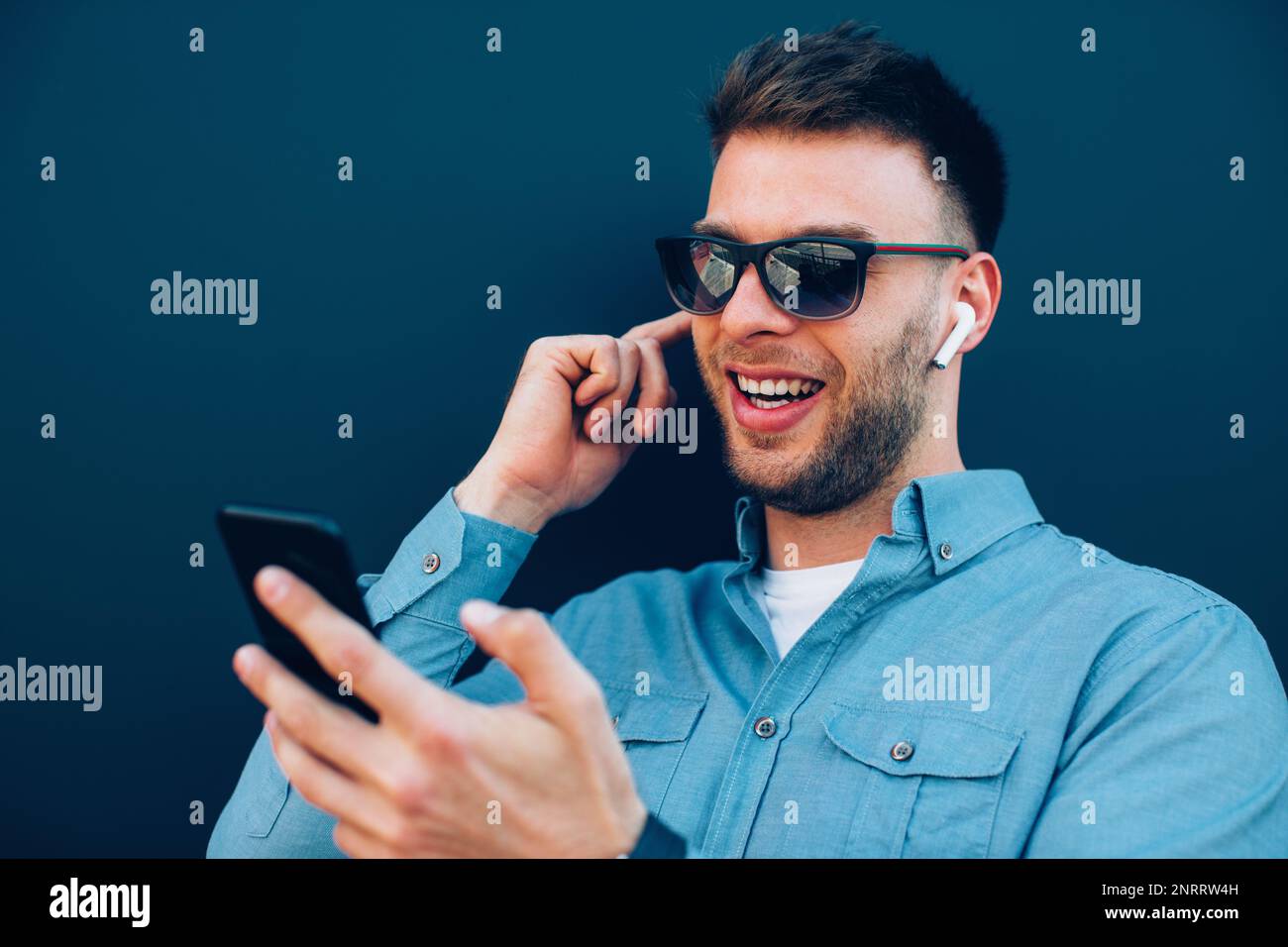 Young man listening to music via wireless earphones and smartphone
