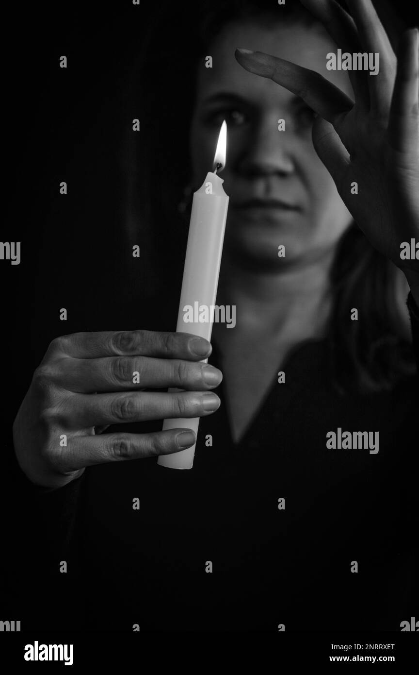 black and white portrait of a woman playing with a candle flame and dripping wax Stock Photo