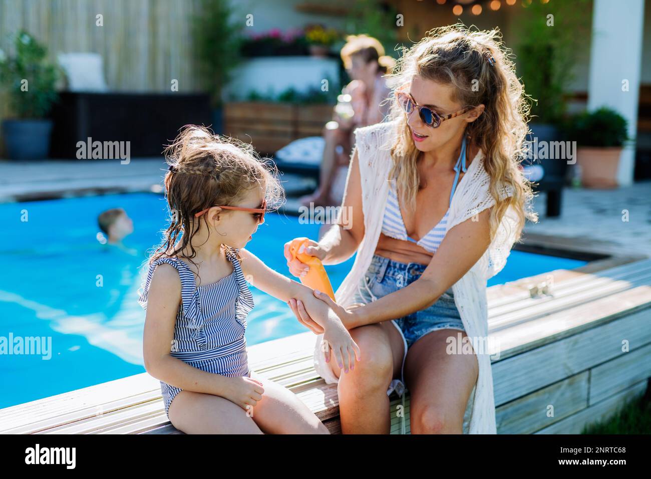Young mother applying sunscreen lotion to her daughter. Safety