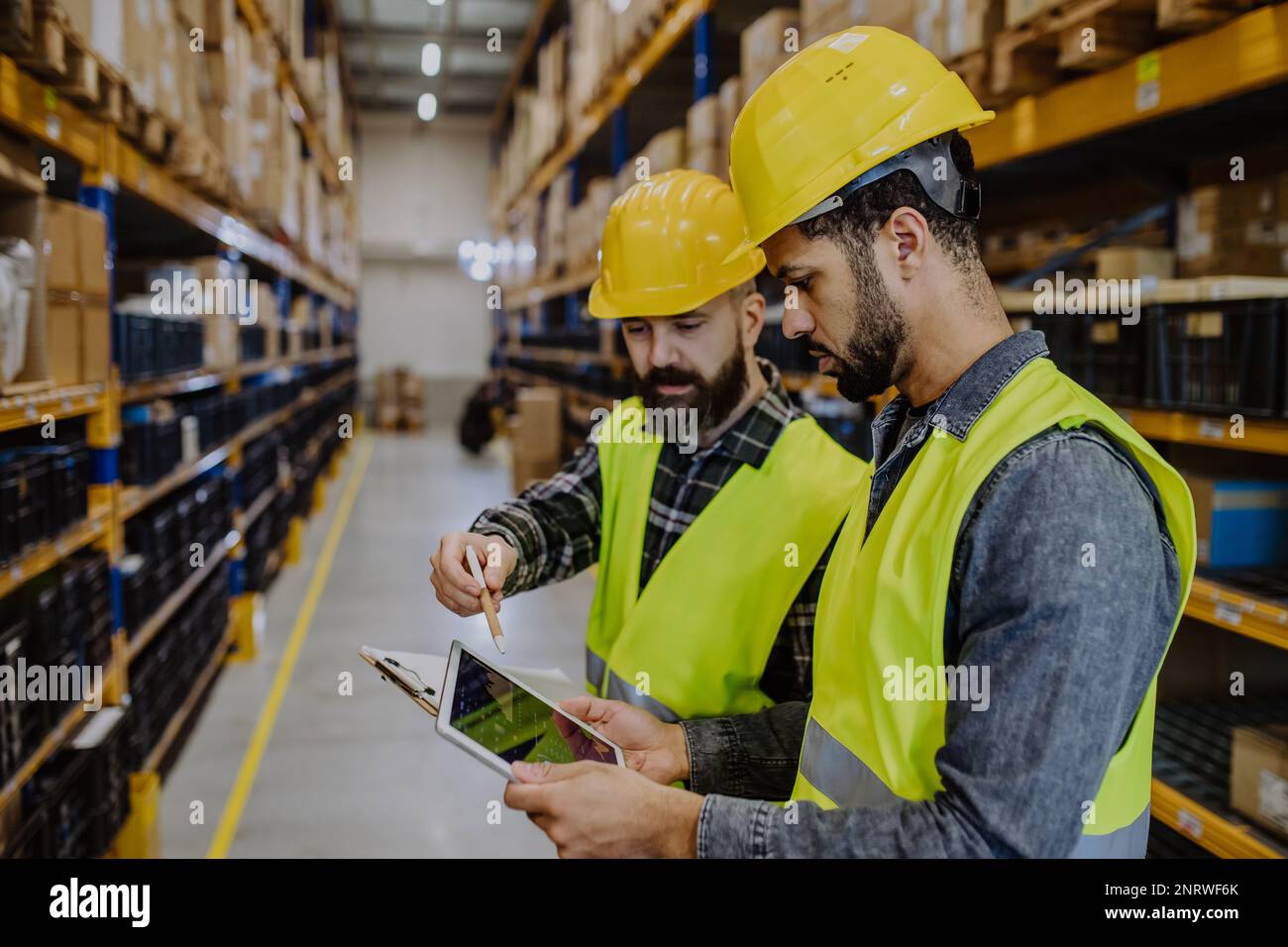 Warehouse workers checking stuff in warehouse with digital system in tablet. Stock Photo