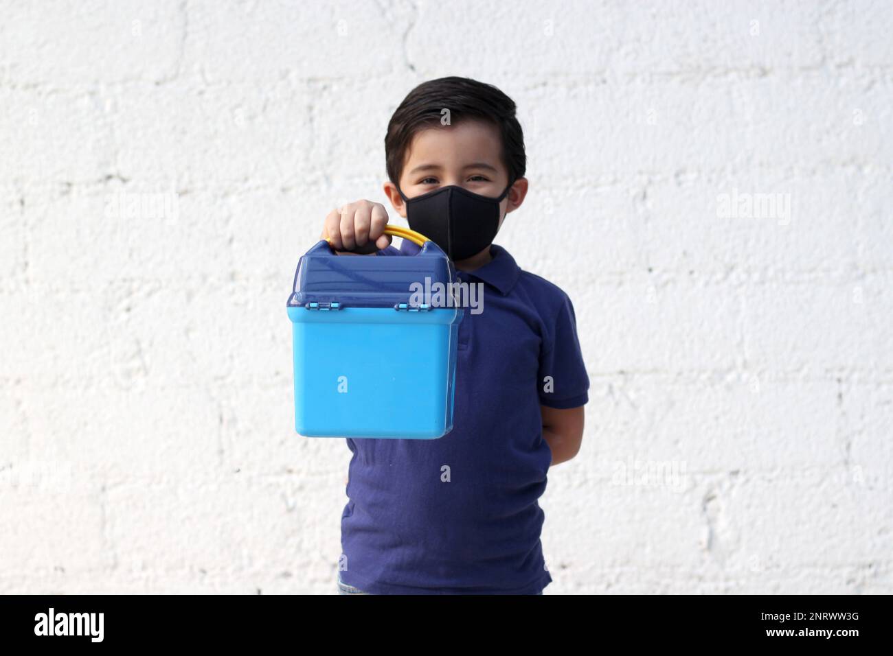 6yearold boy with protective mask, lunch box and colors for back to
