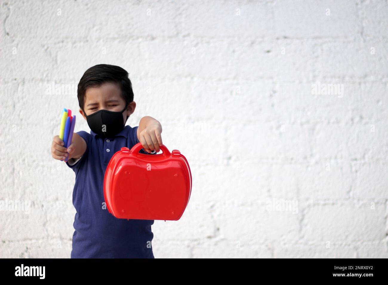 6yearold boy with protective mask, lunch box and colors for back to