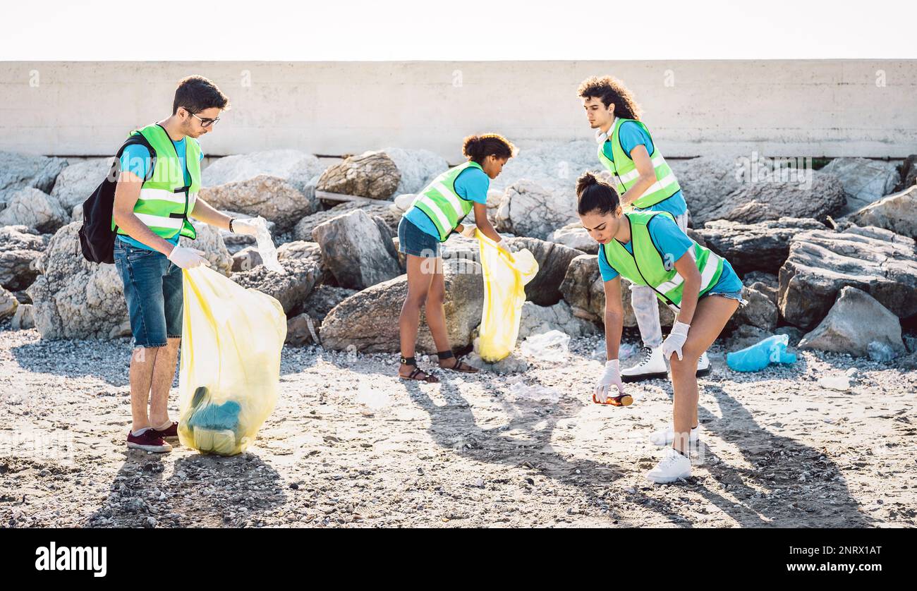 Social volunteers wearing uniform at beach shore cleaning activity over trash garbage - Environment conservation concept for plastic material pollutio Stock Photo