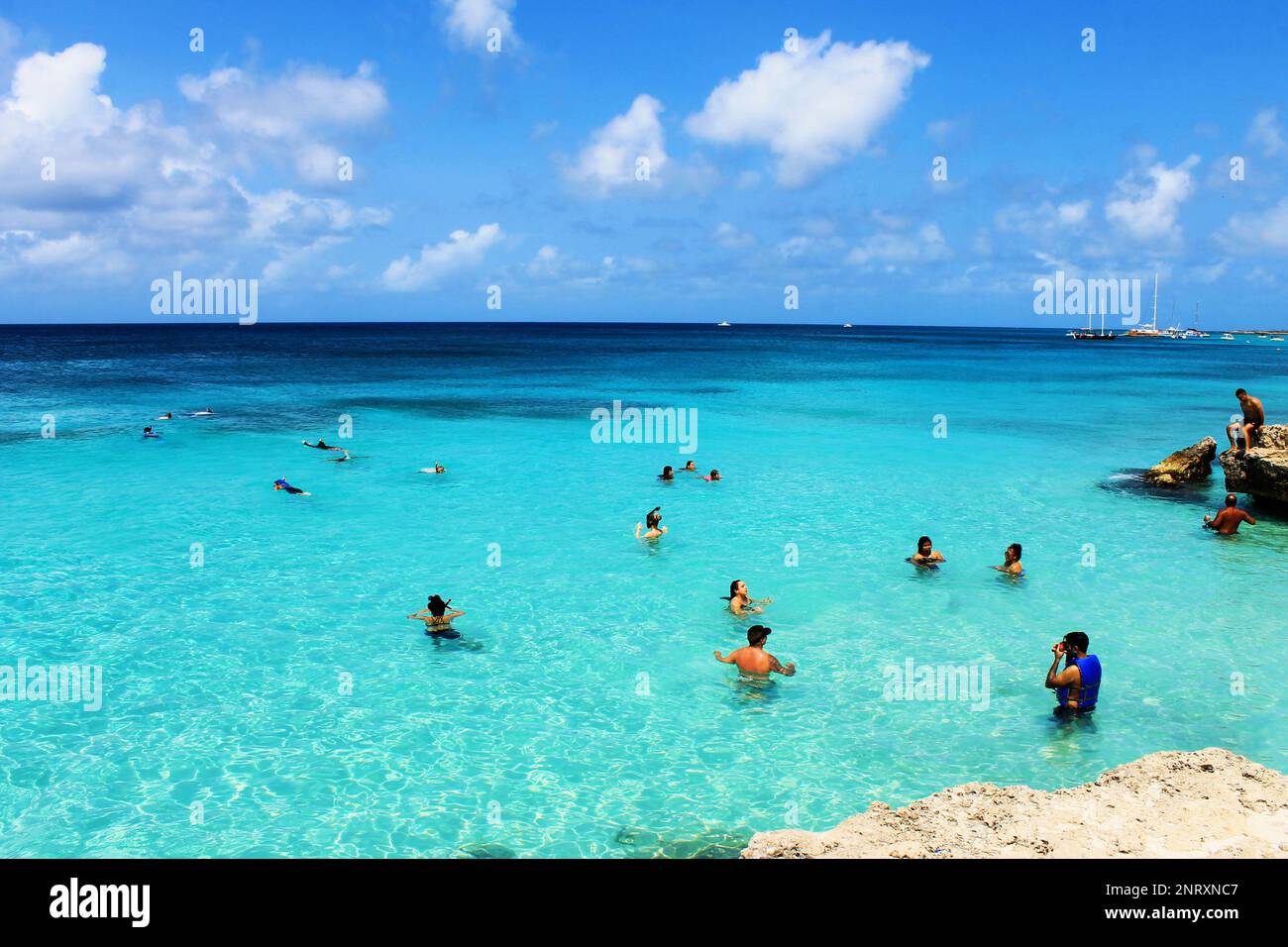 Tres Trapi Beach, Noord, Aruba - March 10, 2022. People on the beach and in the water, Beach is surrounded by a volcanic rock formation. Stock Photo