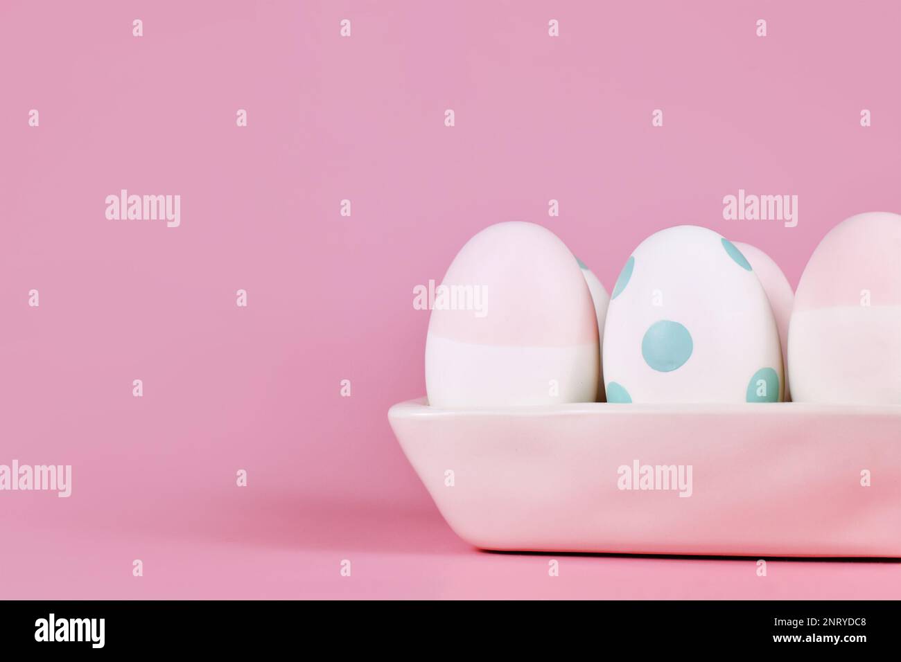 Pastel colored painted Easter eggs in egg box on pink background with copy space Stock Photo