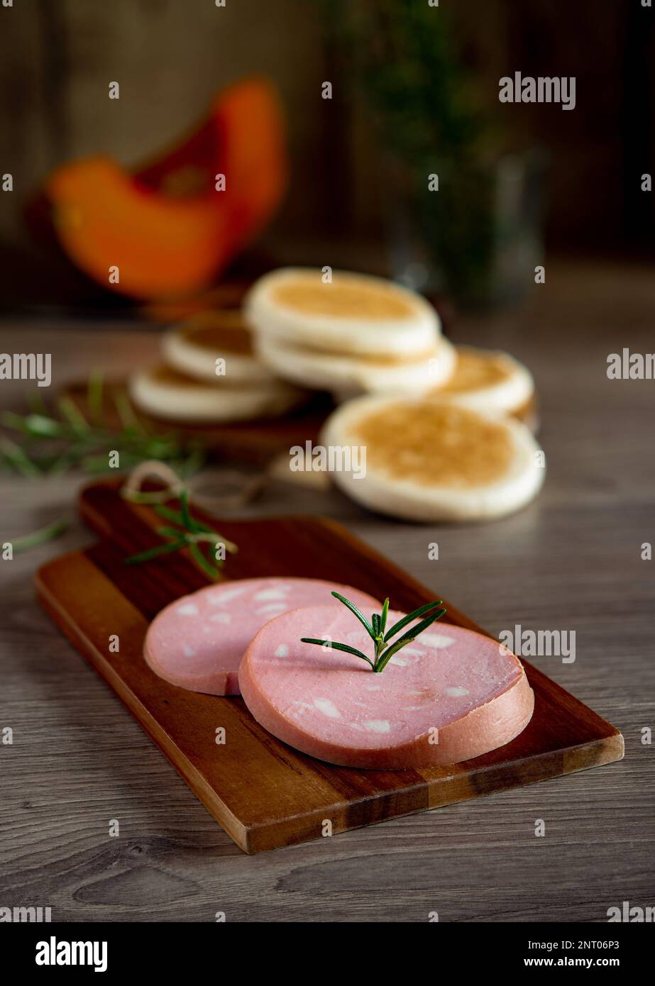 slices of Bologna IGP mortadella on a rustic wooden cutting board and Modenese tigelle Stock Photo