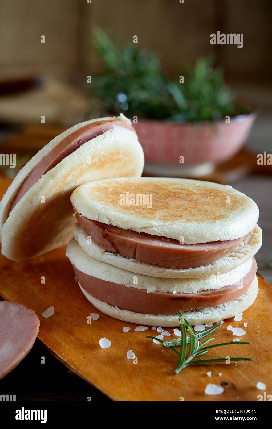 slices of Bologna IGP mortadella on a rustic wooden cutting board and Modenese tigelle Stock Photo