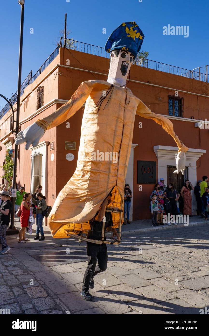 A mono de calenda or giant puppet in a uniform costume dances in the Santo Domingo Plaza in Oaxaca, Mexico.  Mono de calenda translates to parade monk Stock Photo