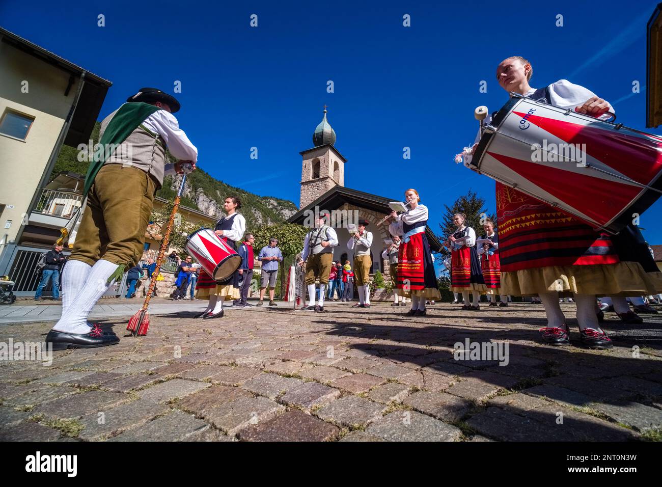 Traditionally dressed people play music during the Almabtrieb, the cattle drive from the mountain pasture, in the village of Fai della Paganella. Stock Photo