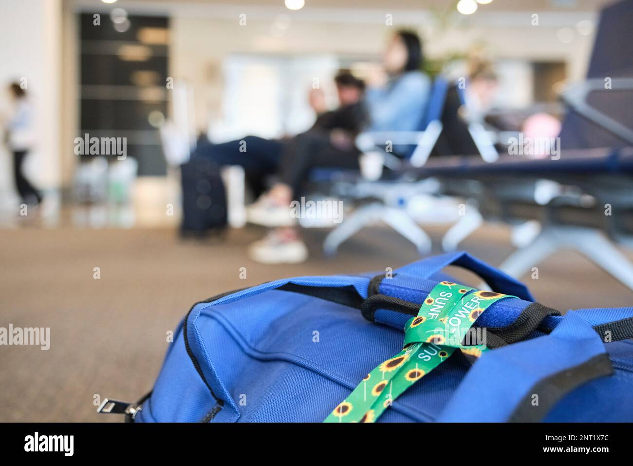 Lanyard of sunflowers, symbol of people with invisible or hidden disabilities, tied on a travel bag on the floor of an airport. Stock Photo