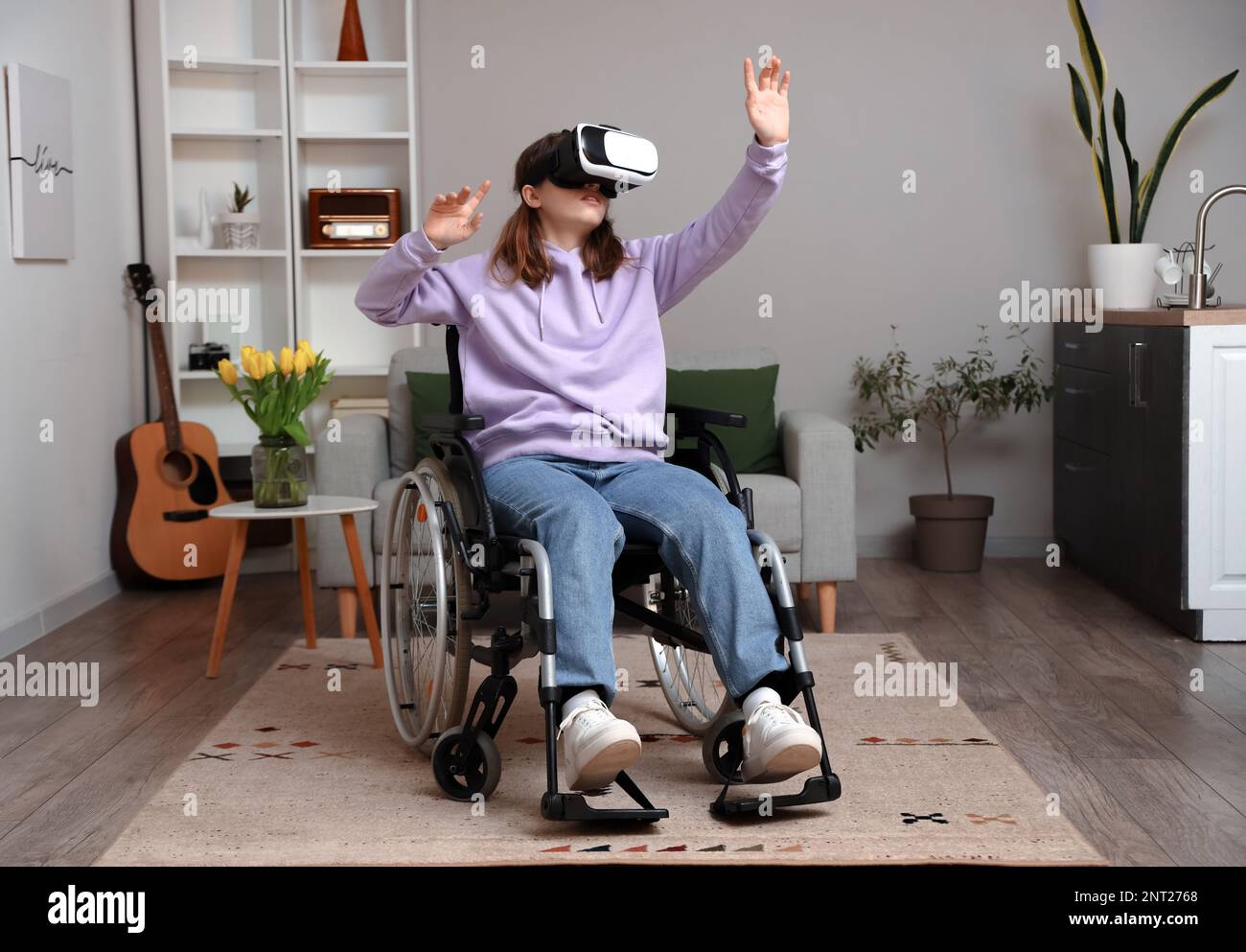 Young woman in wheelchair using VR glasses at home Stock Photo - Alamy