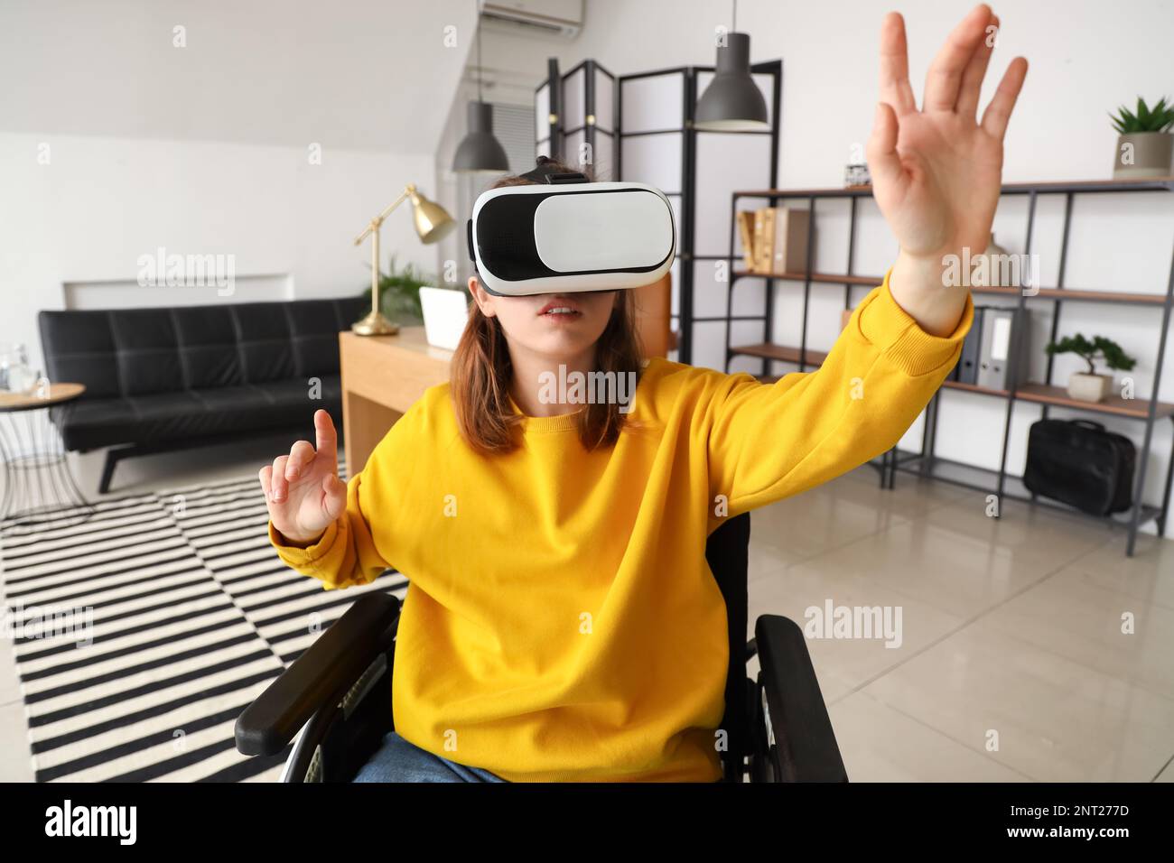 Young woman in wheelchair using VR glasses in office Stock Photo - Alamy
