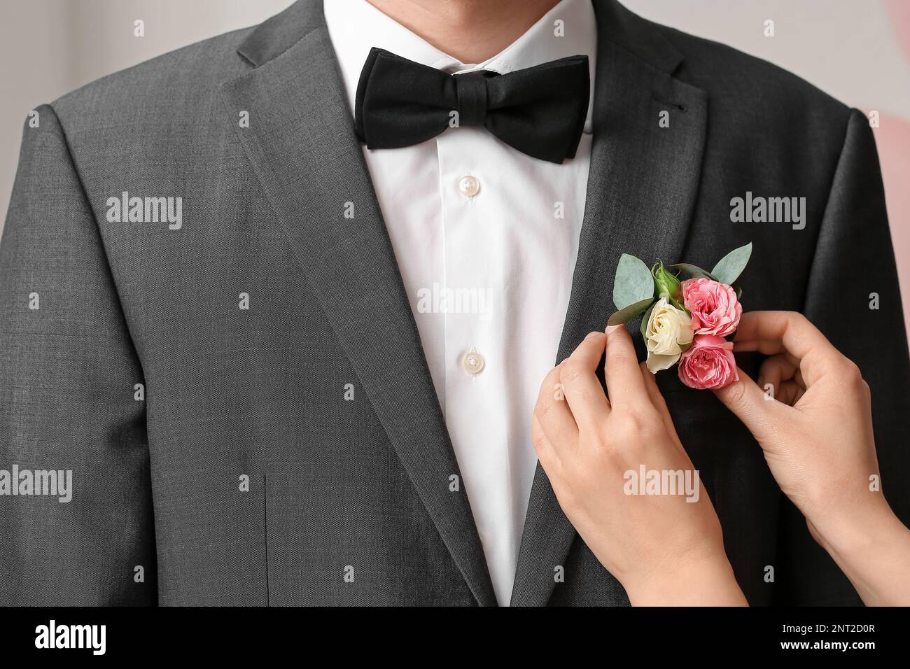 Young woman pinning boutonniere on her prom date's suit, closeup Stock
