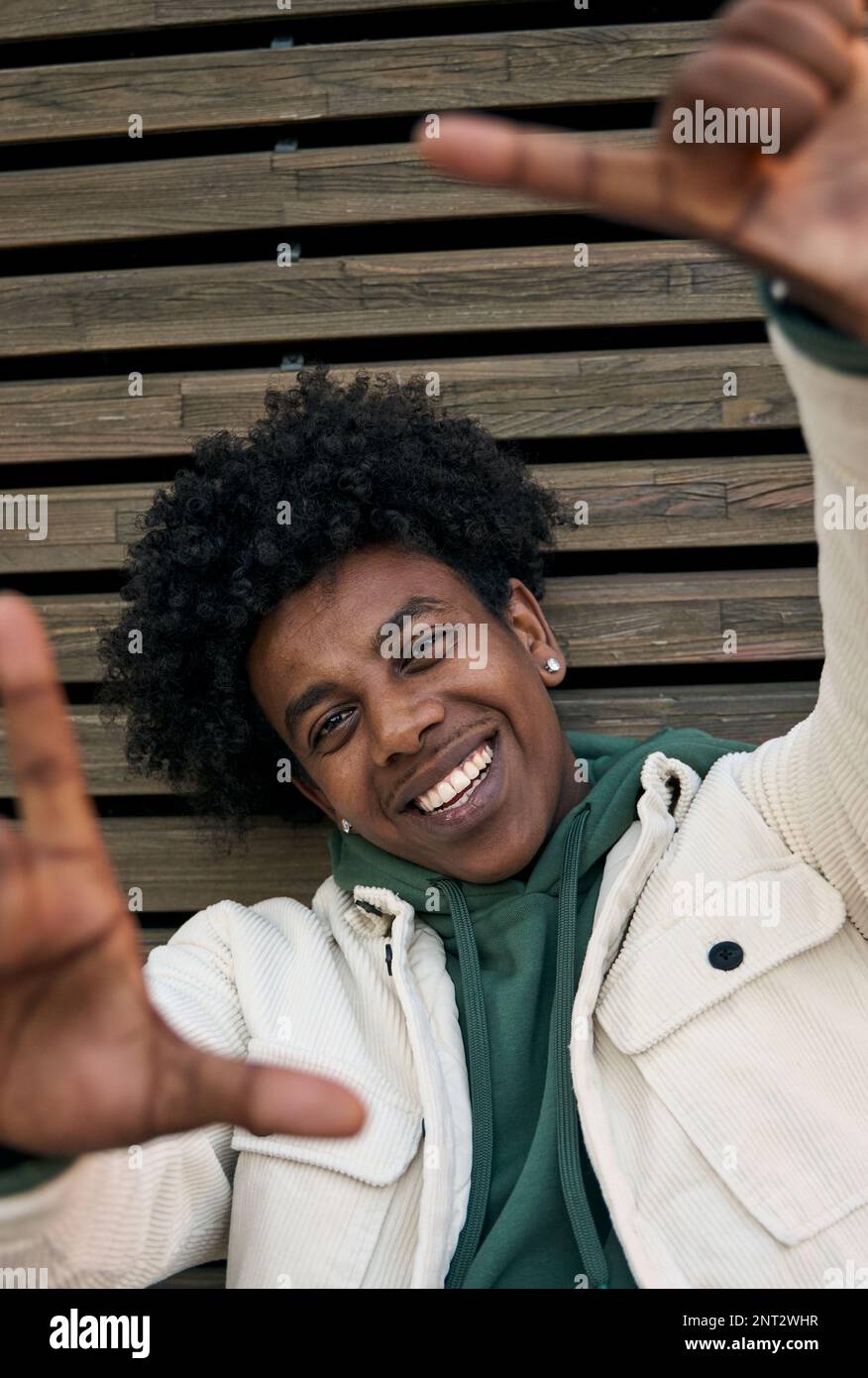 Happy African American teen boy taking selfie at wooden wall. Portrait Stock Photo