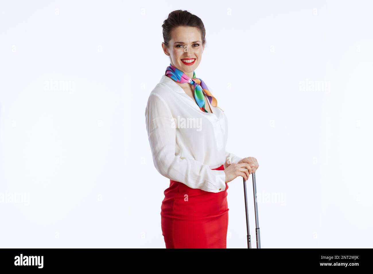 smiling stylish air hostess woman isolated on white background in uniform with travel bag. Stock Photo