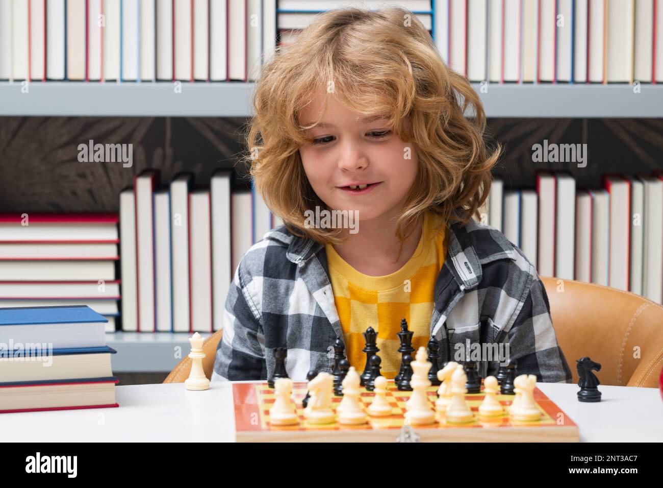 Chess school for children. Little kid play chess. Thinking child. Chess game for kids. Intelligent, smart and clever school boy. Stock Photo