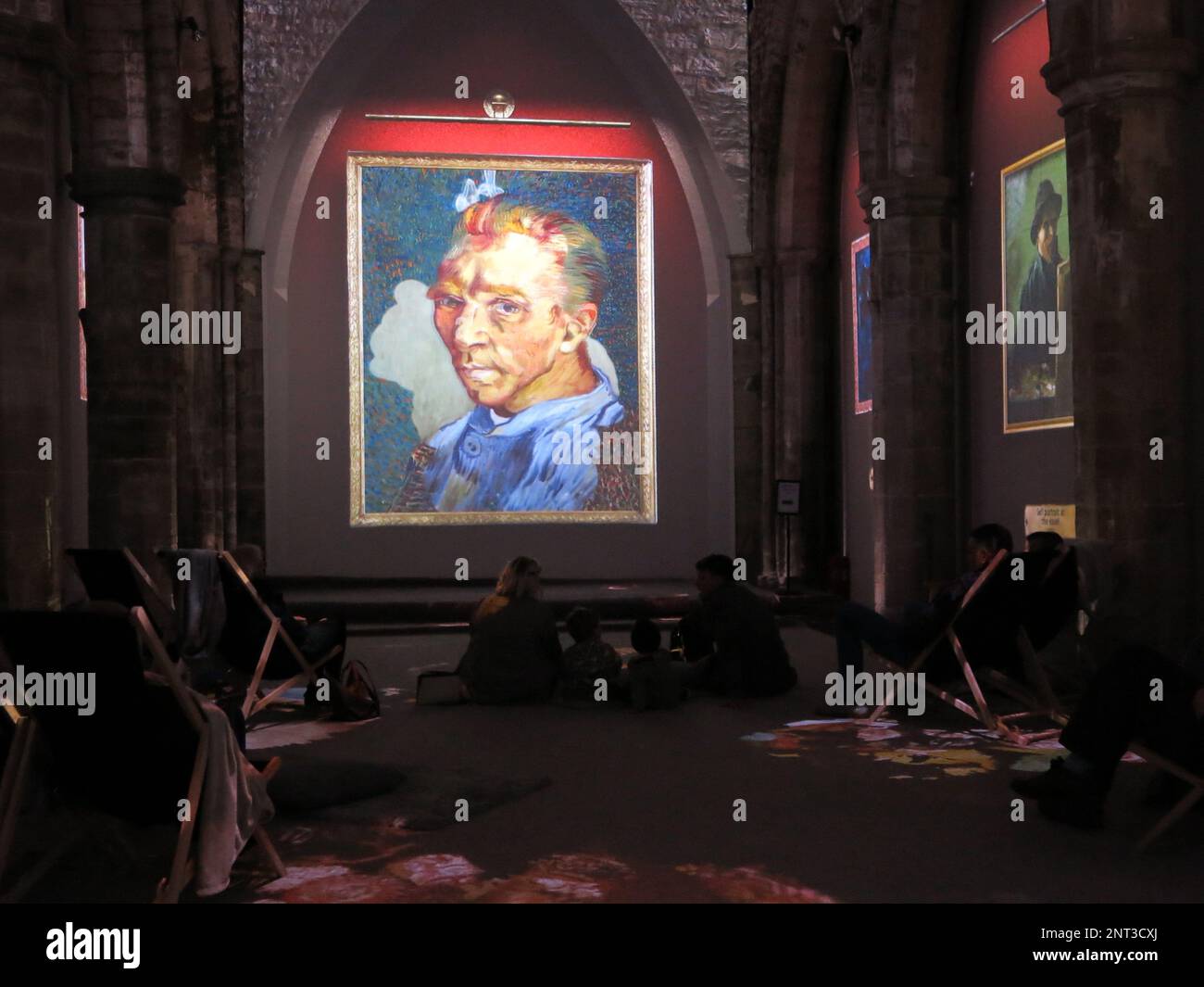 Portrait of Van Gogh gallery visitors sit in deckchairs or cushions on