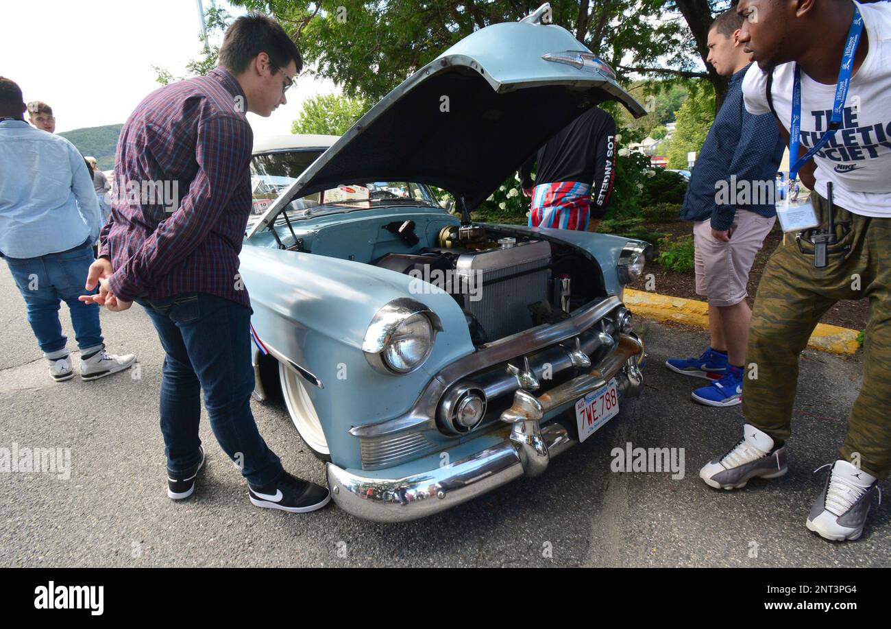 Car enthusiasts bend down to see this lowriding 1953 Chevy Belair
