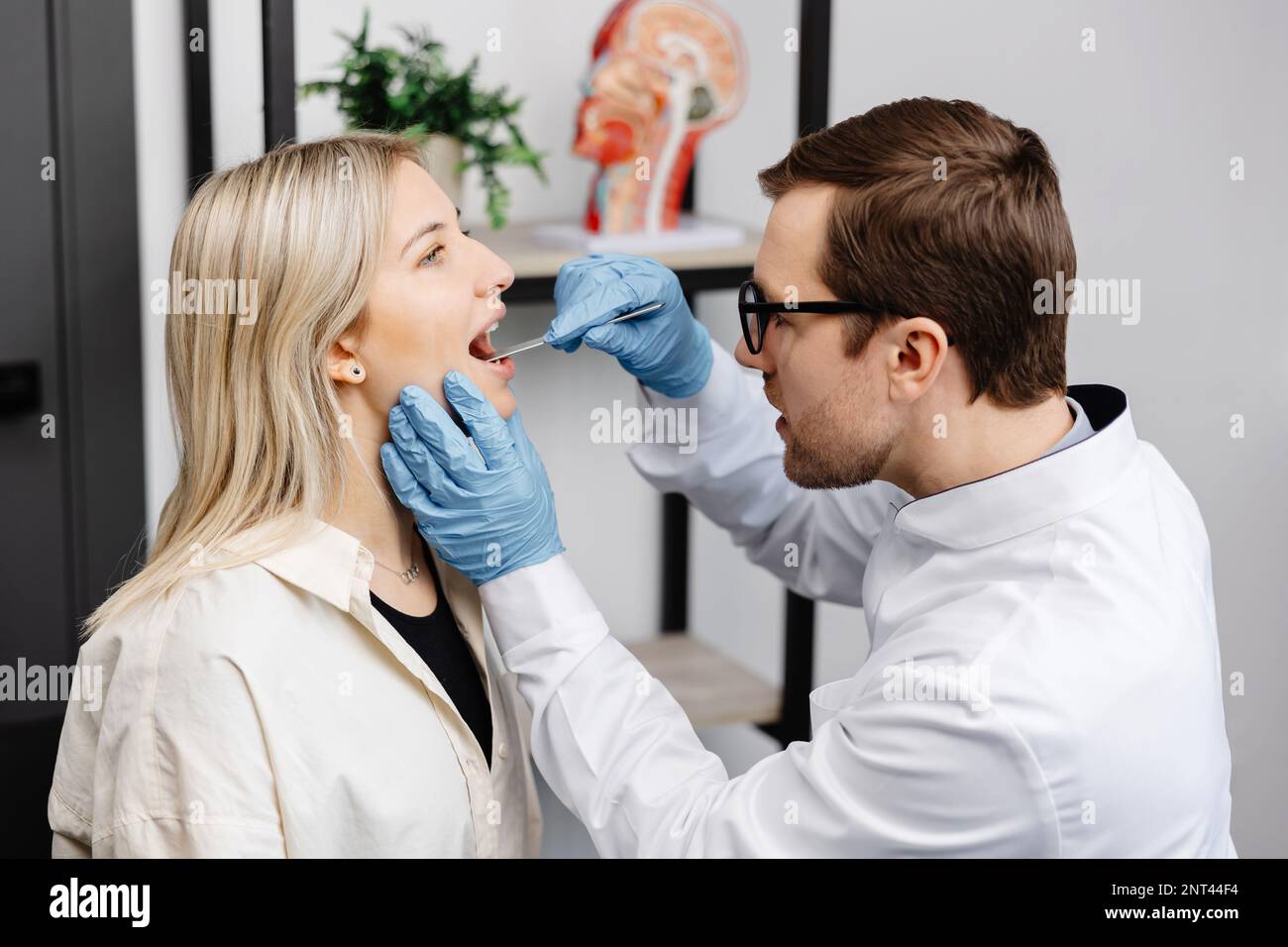 Doctor using inspection spatula to examine patient throat. ENT doctor
