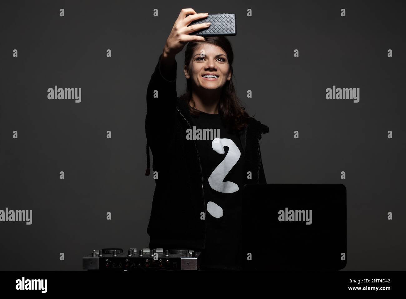 Female DJ on a mixer. Girl playing texhno music and takin photos with phone. Stock Photo