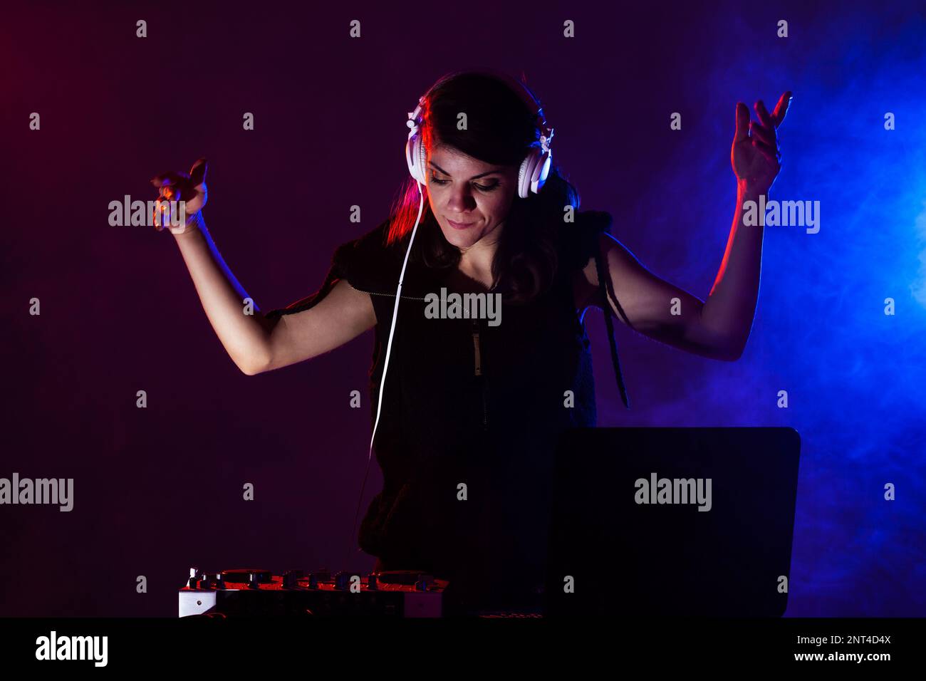 Female DJ playing music on a mixer. Red and blue lights and smoke in
