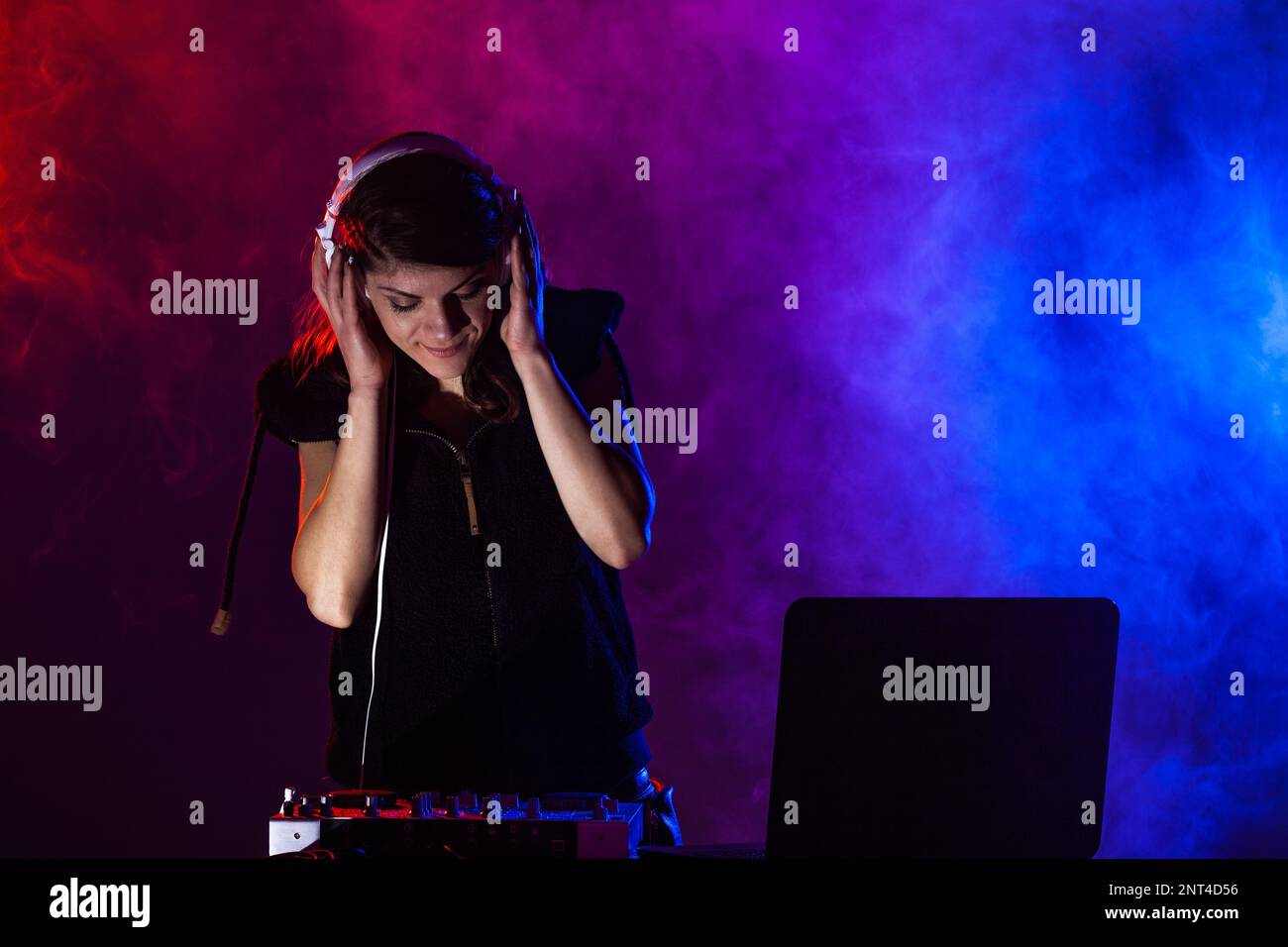 Female DJ playing music on a mixer. Red and blue lights and smoke in