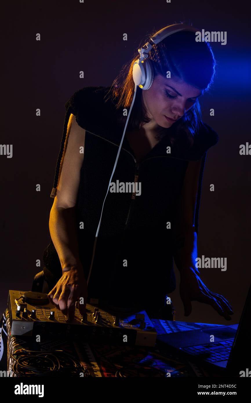 Female DJ playing music on a mixer. Blue light flare visible Stock Photo