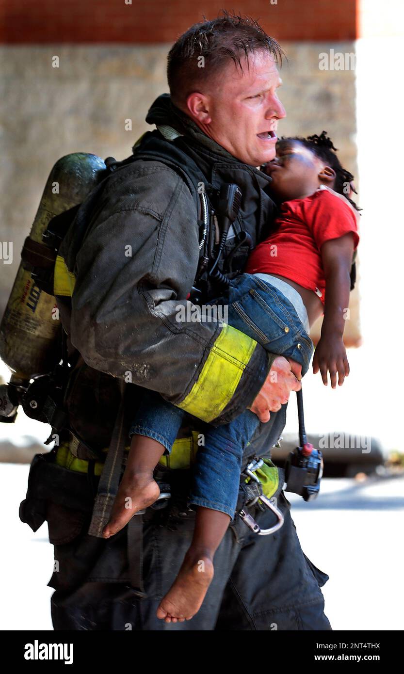 St. Louis firefighter Josh Roth carries a girl from a burning apartment ...