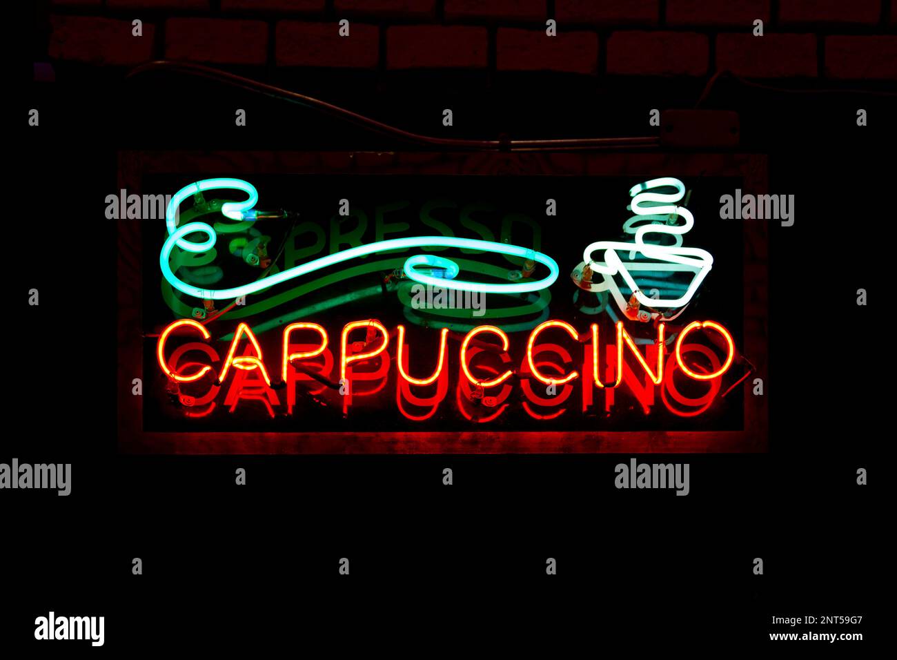 Neon light on a brick wall saying "Cappuccino". Stock Photo