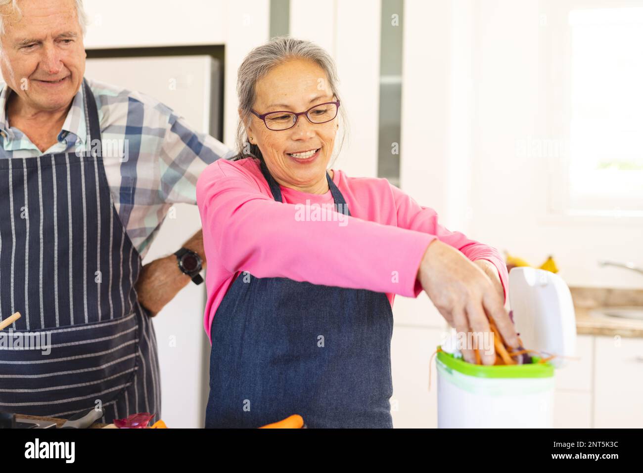 Happy senior diverse couple cleaning waste in kitchen Stock Photo