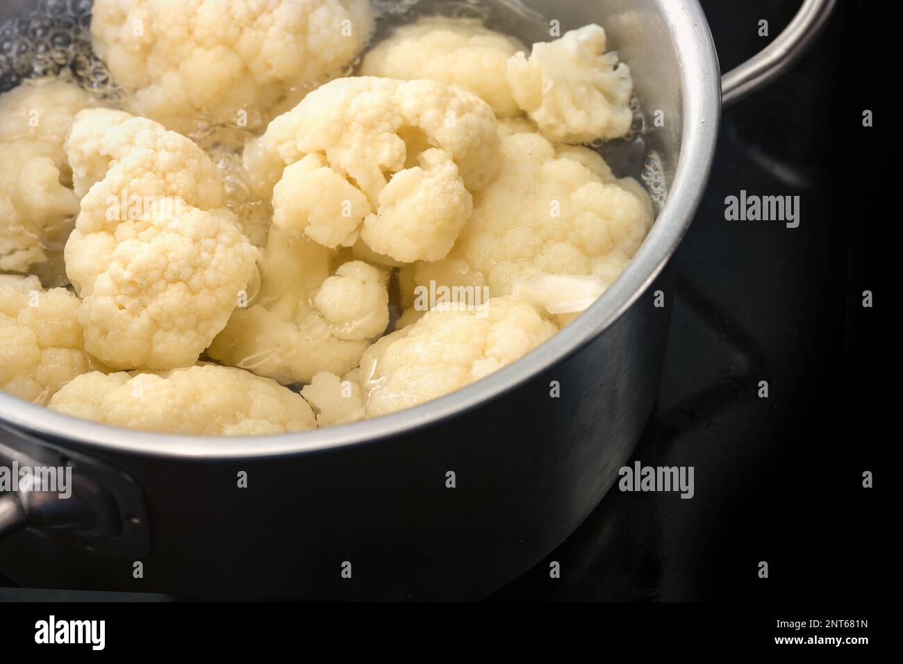 Cauliflower in boiling water in a stainless steel pot on a black cooktop, healthy vegetable cooking, copy space, selected focus, narrow depth of field Stock Photo