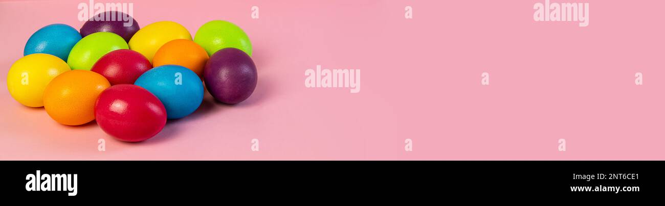 Wide Easter banner empty. Multi-colored eggs on a pink background. Stock Photo