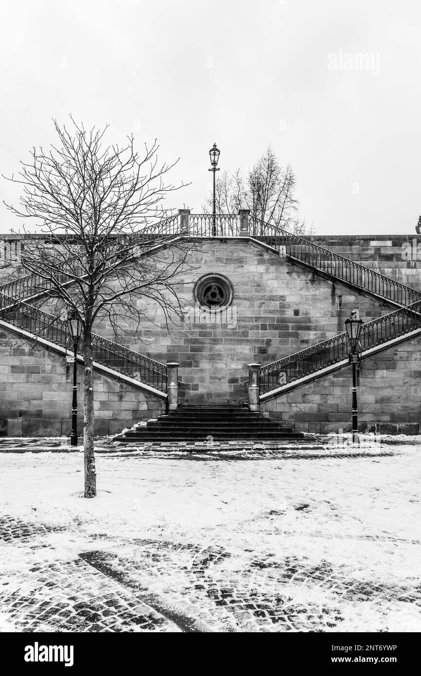 Historic stone staircase leading from Kampa Island to Charles Bridge in Prague, Czech Republic. The winter scenery adds to the picturesque view. Black and white photography. Stock Photo