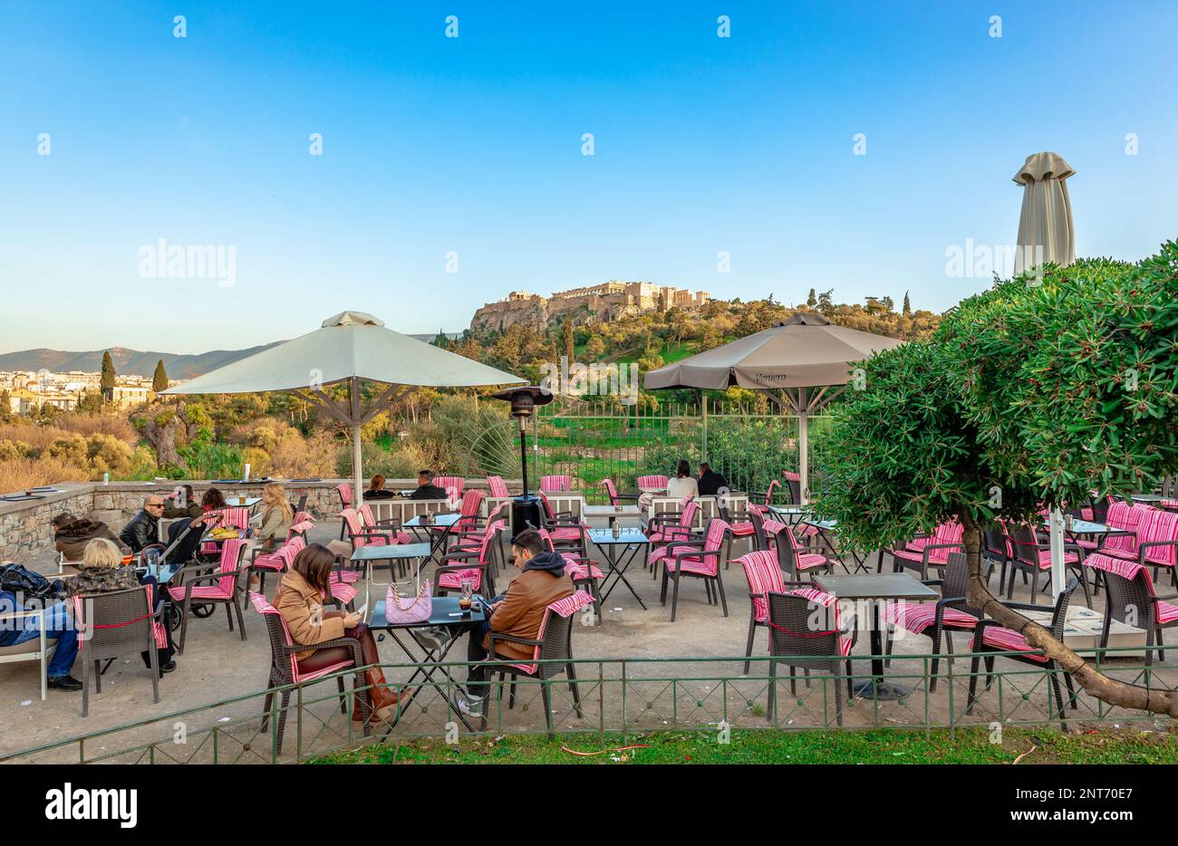 Seated people  in a sidewalk cafe, in Thissio district, with the Acropolis hill in the background. Athens, Greece. Stock Photo