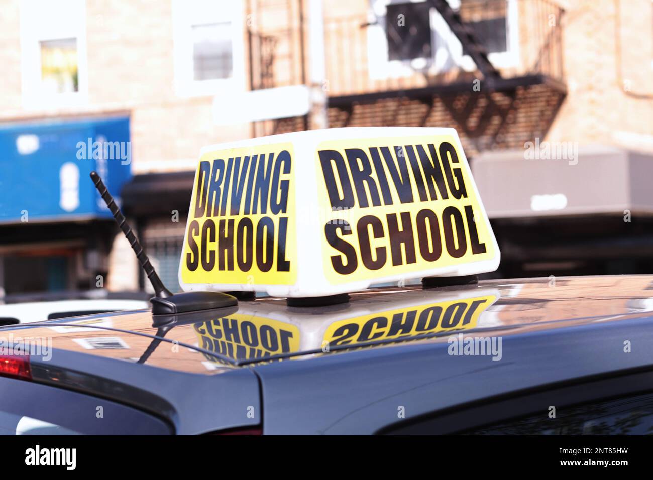 Close up of large driving school sign on the roof of a practice car in a busy city street Stock Photo
