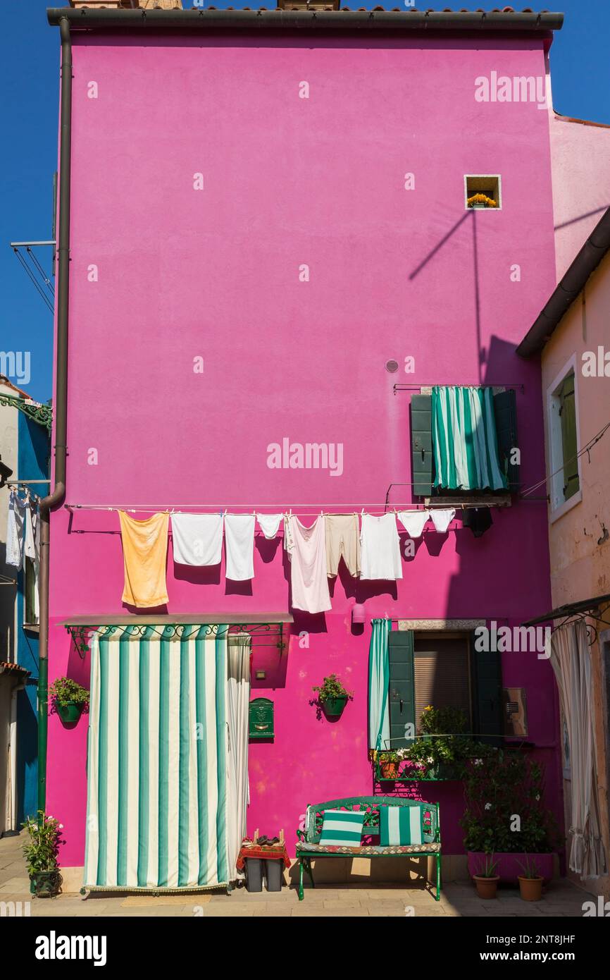 Clothesline on wall of pink stucco house decorated with green and white ...