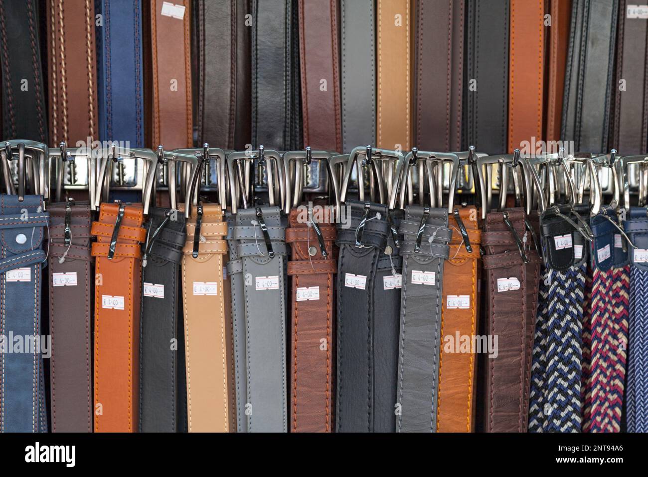 Closeup on a stack of leather belts for sale on a market stall in
