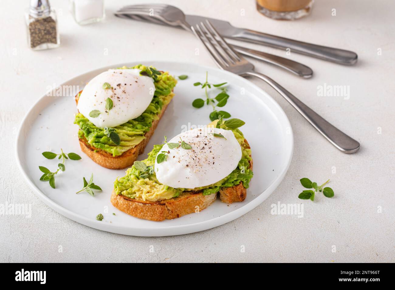 Sourdough toast with mashed avocado and poached eggs with herbs, healthy breakfast idea Stock Photo