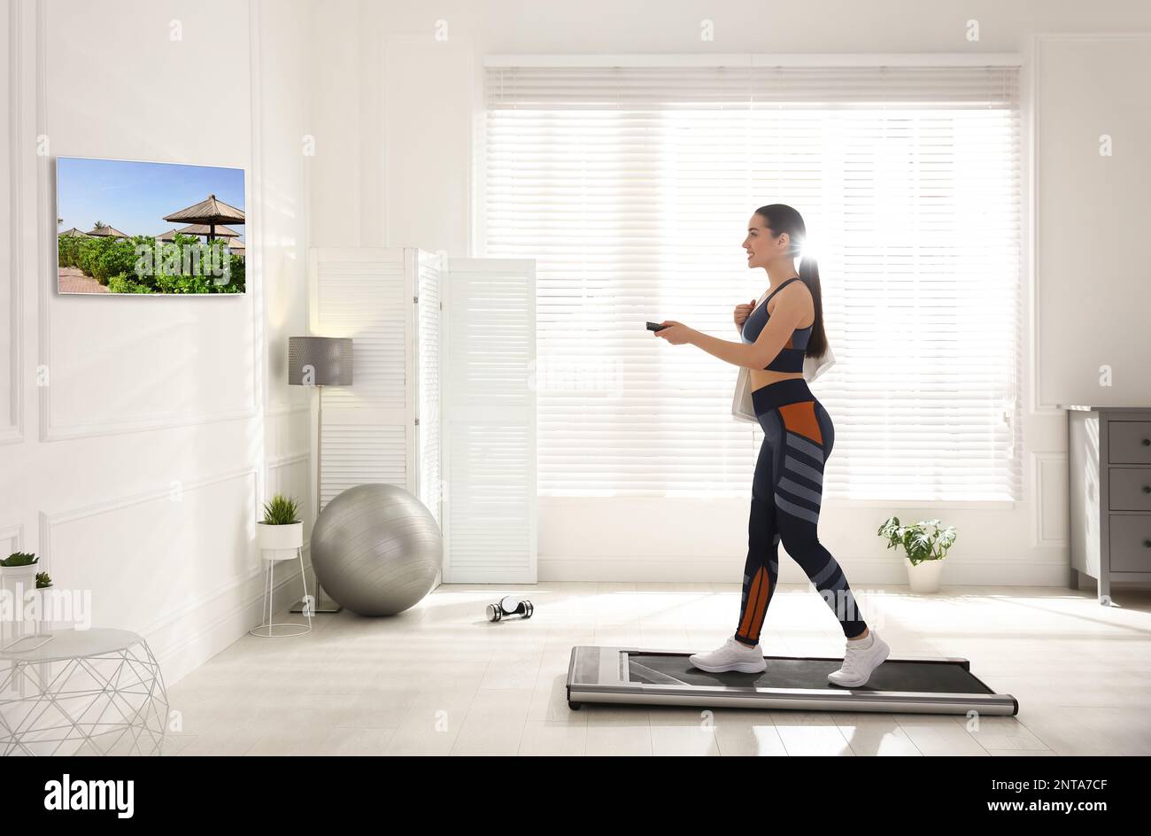 Sporty woman with remote control training on walking treadmill and ...