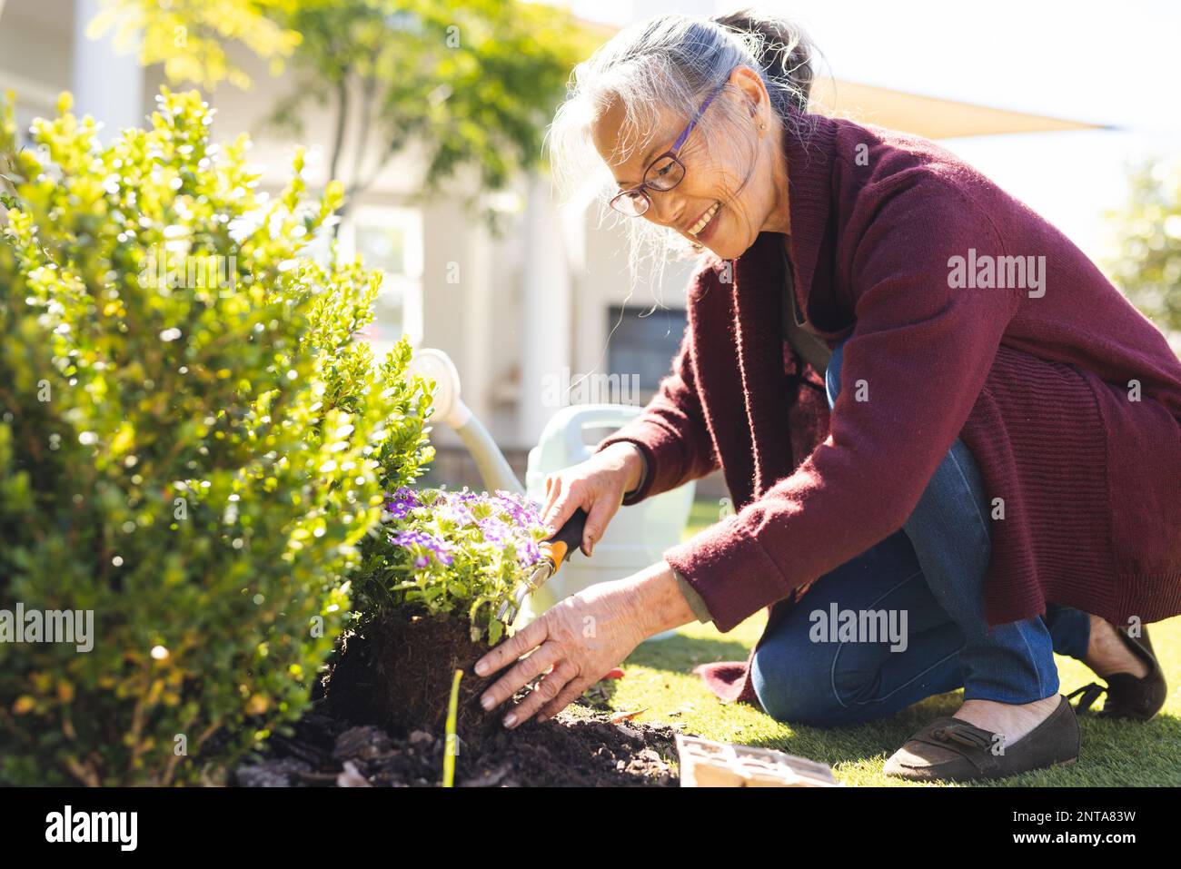 Happy senior asian woman gardening and replanting flowers Stock Photo