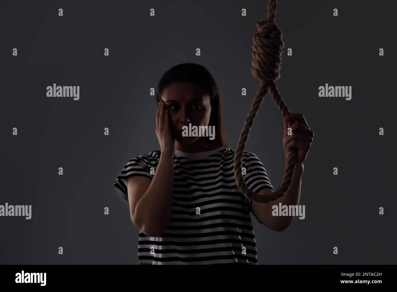Depressed woman with rope noose on grey background Stock Photo