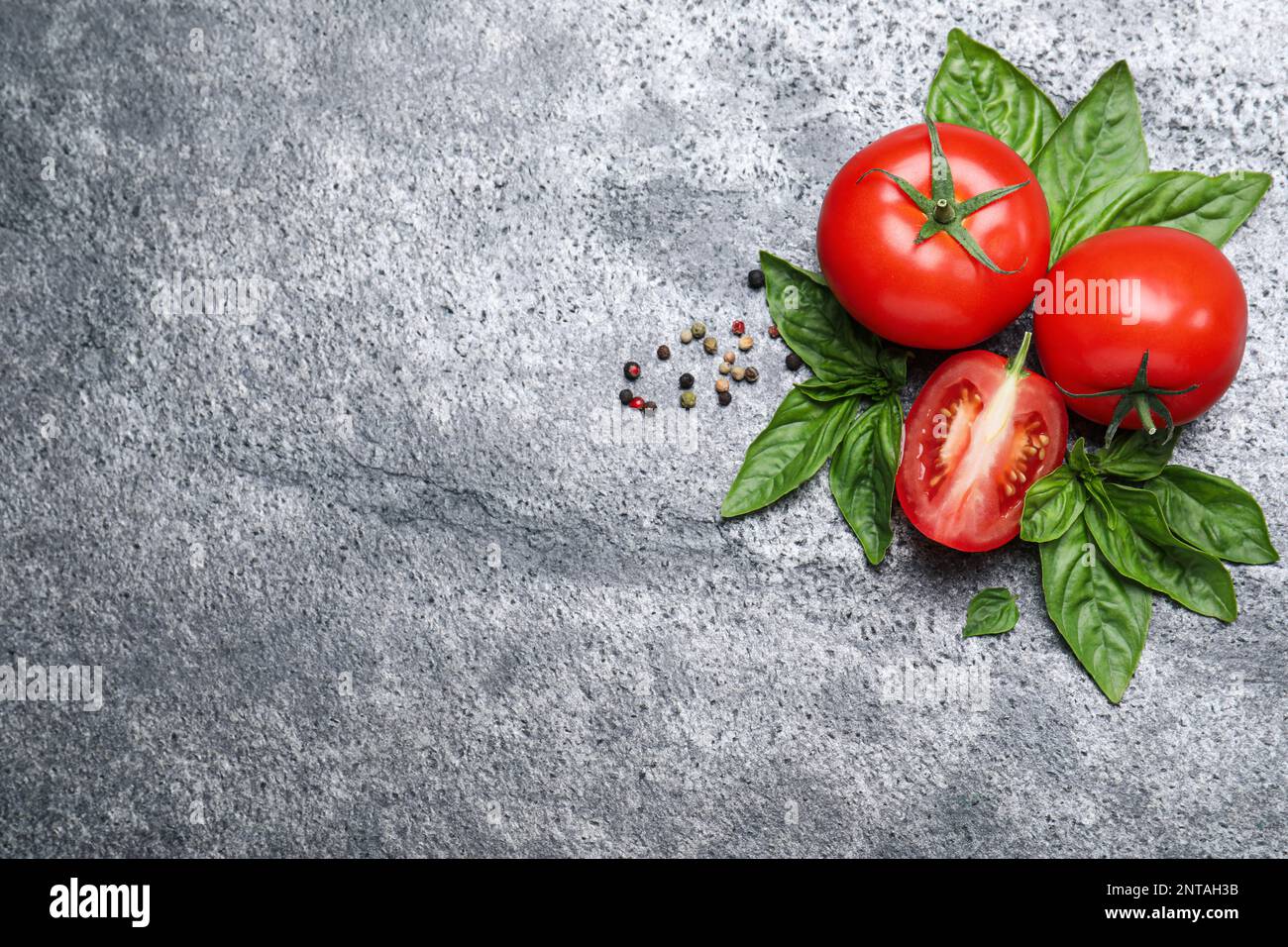 Flat lay composition with fresh basil leaves and tomatoes on grey table ...