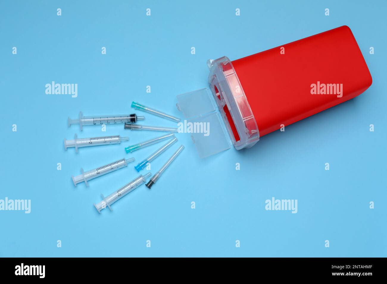 Disposable syringes, needles and sharps container on light blue